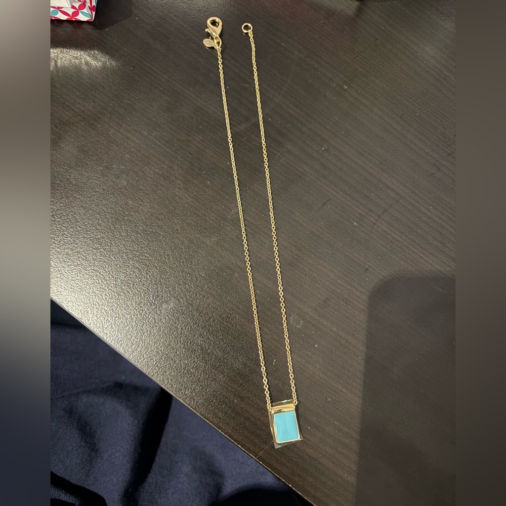 Gold necklace with light blue stone.